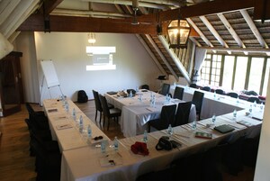 Una sala de conferencias con largas mesas, sillas y una pizarra.