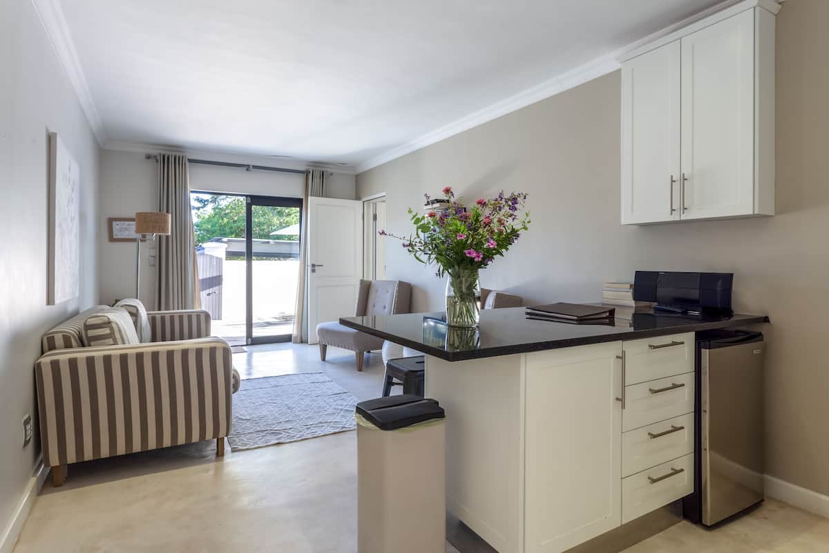 A modern kitchen with a central island, a dining area with a sofa, and a view to the outside.