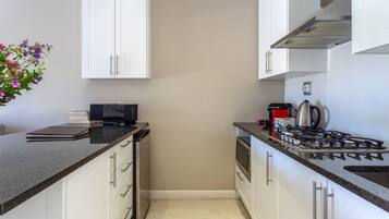 A modern kitchen with white cabinets, a gas stove, and a microwave.