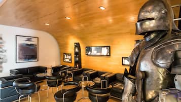 Ein modernes Interieur mit Ledersofas und -sesseln, einer großen Metallskulptur und gerahmten Bildern an den Wänden.