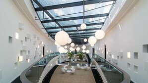 A modern interior with a glass ceiling, circular seating, and a central staircase. - Hotel Schloss Montabaur (Montabaur)