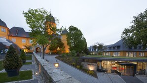 A courtyard with a reception area, stone pathway, and surrounding buildings with traditional architecture. - Hotel Schloss Montabaur (Montabaur)