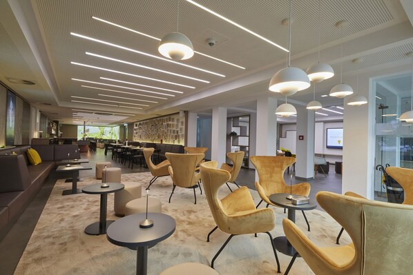 Ein moderner Lounge-Bereich mit Sofas, runden Tischen und Pendelleuchten.