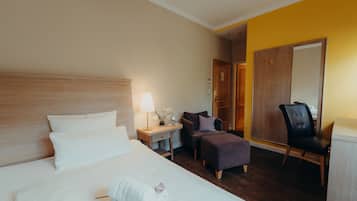 Una habitació d'hotel amb un llit, una tauleta de nit, una làmpada, una cadira i un armari.