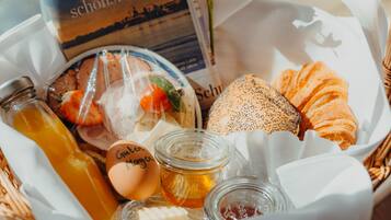 A basket containing a variety of food items including bread, a bottle of juice, and a book titled "Hamburgs schönste Bilder".