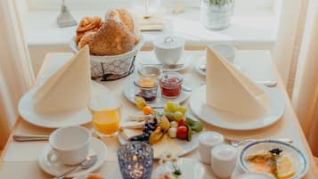 Disposição para o pequeno-almoço com pratos de comida, chávenas e vista pela janela.