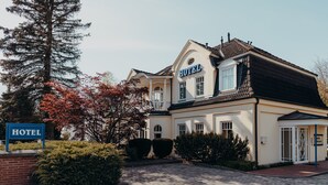 A hotel with a classic architectural style, featuring a prominent 'HOTEL' sign, a paved driveway, and well-maintained landscaping.