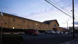 A parking lot with several cars and a building with a flat roof and brick walls. - Knights Inn South Amboy (South Amboy)