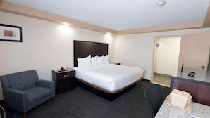 A hotel room with a bed, a desk, a chair, a couch, and a small table. - Knights Inn South Amboy (South Amboy)