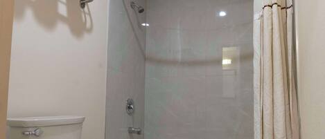 A bathroom with a toilet, bathtub, shower curtain, and a towel rack.