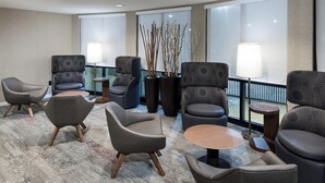 Un hall d’hôtel doté d’un mobilier moderne, comprenant des canapés et des fauteuils, une table basse et un vase décoratif orné de branches.