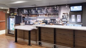 Un espace bar moderne doté d’un long comptoir, d’une vitrine réfrigérée et d’un panneau affichant le menu.