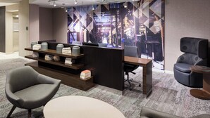 Un espace de bureau moderne comprenant un comptoir d’accueil, un coin salon et une grande fresque murale abstraite.