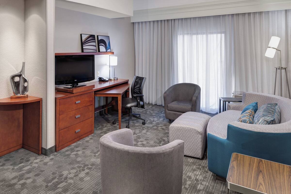 Ein Hotelzimmer mit Schreibtisch, Fernseher und Sitzecke.