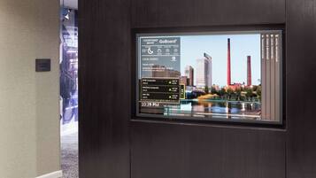 A digital display in a hotel lobby with a cityscape view, including tall buildings and a body of water.
