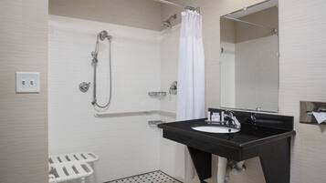 A modern bathroom with a black sink, white shower, and a white toilet with a safety bar.