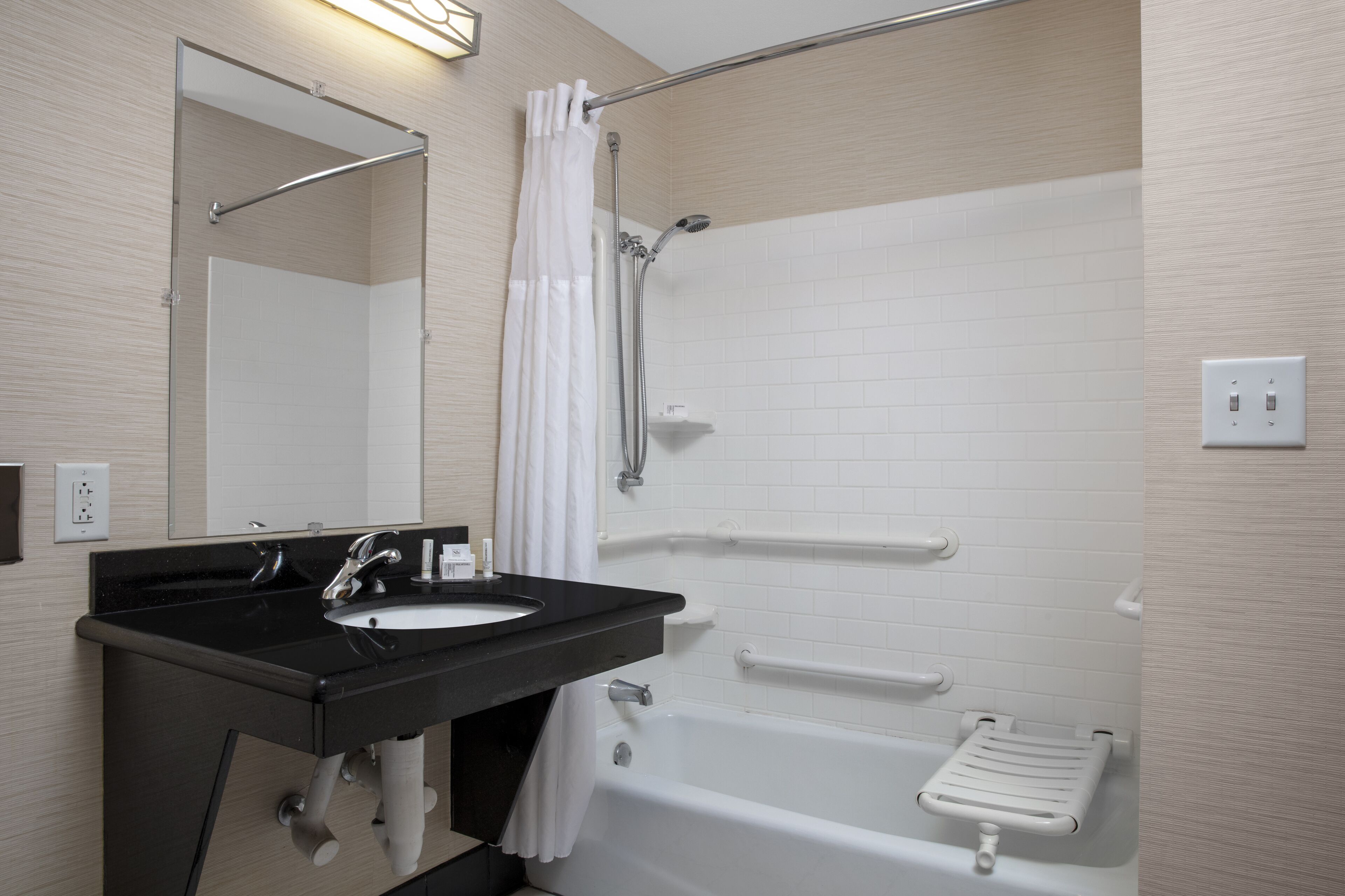 Une salle de bain moderne avec un lavabo noir, une baignoire blanche et une douche dotée d’une porte en verre.
