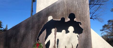 Un monumento con la silueta de un soldado sosteniendo a un niño, una corona y una bandera.