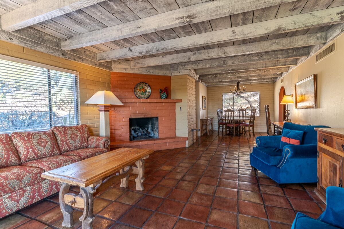 A rustic living room with a fireplace, a sofa, a blue couch, and a dining area.