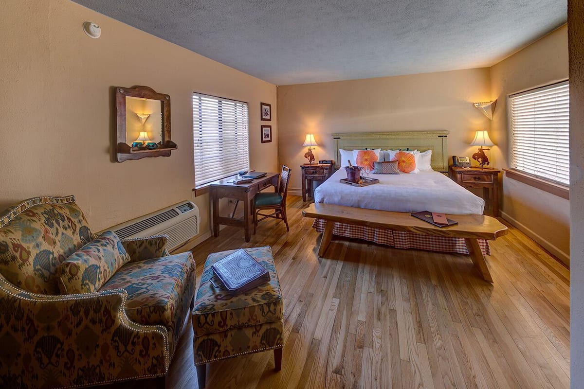 Une chambre d’hôtel avec un grand lit, un canapé, un fauteuil, un bureau et une petite table.