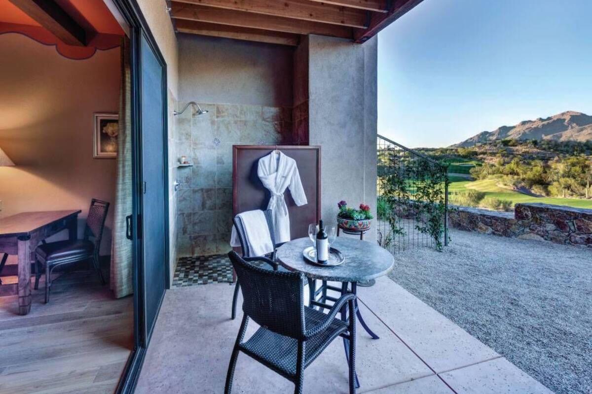 A patio with a round table and chairs, a hanging robe, and a view of a mountainous landscape.