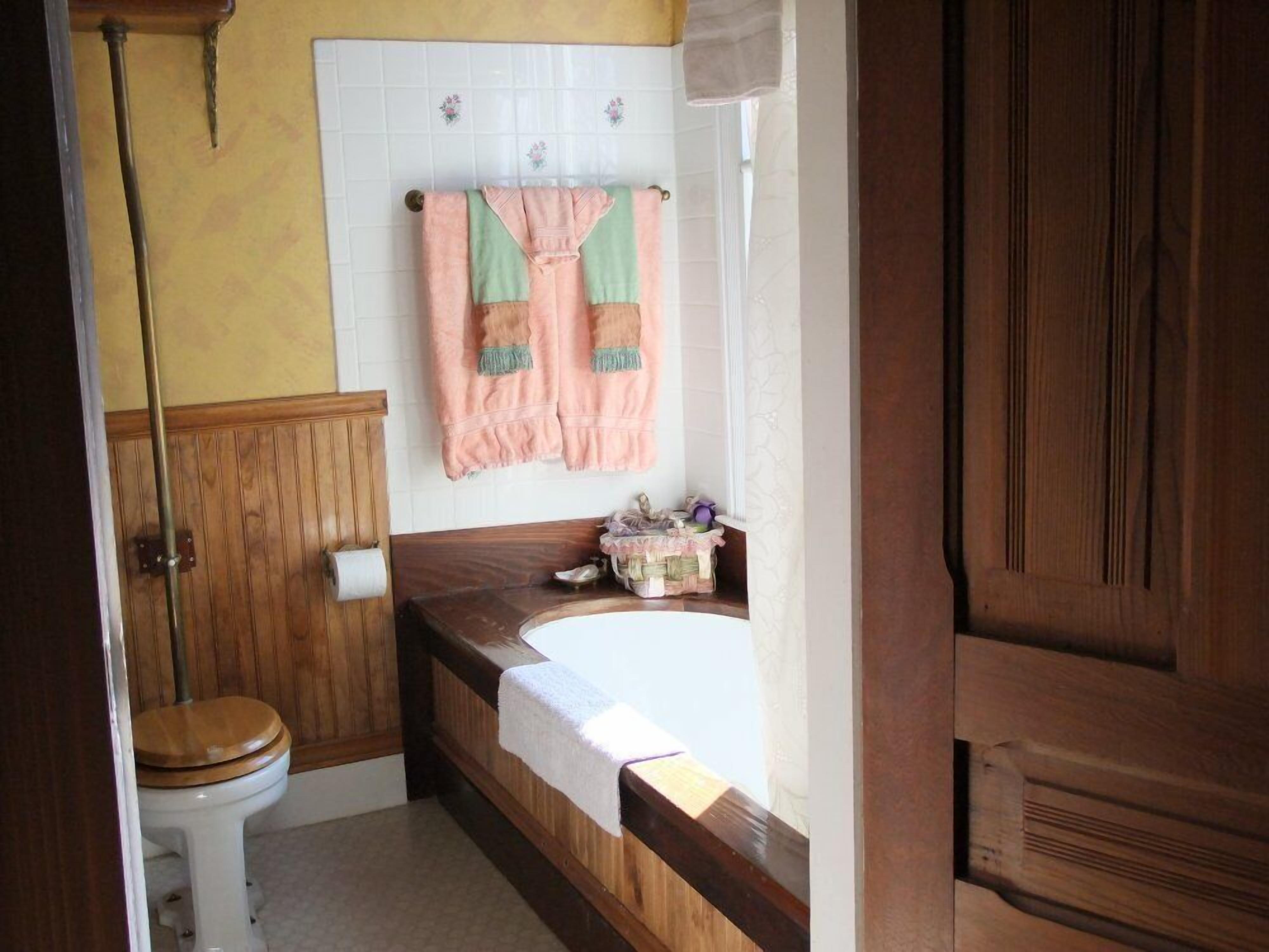 A bathroom with a wooden vanity, a white toilet, and a bathtub.
