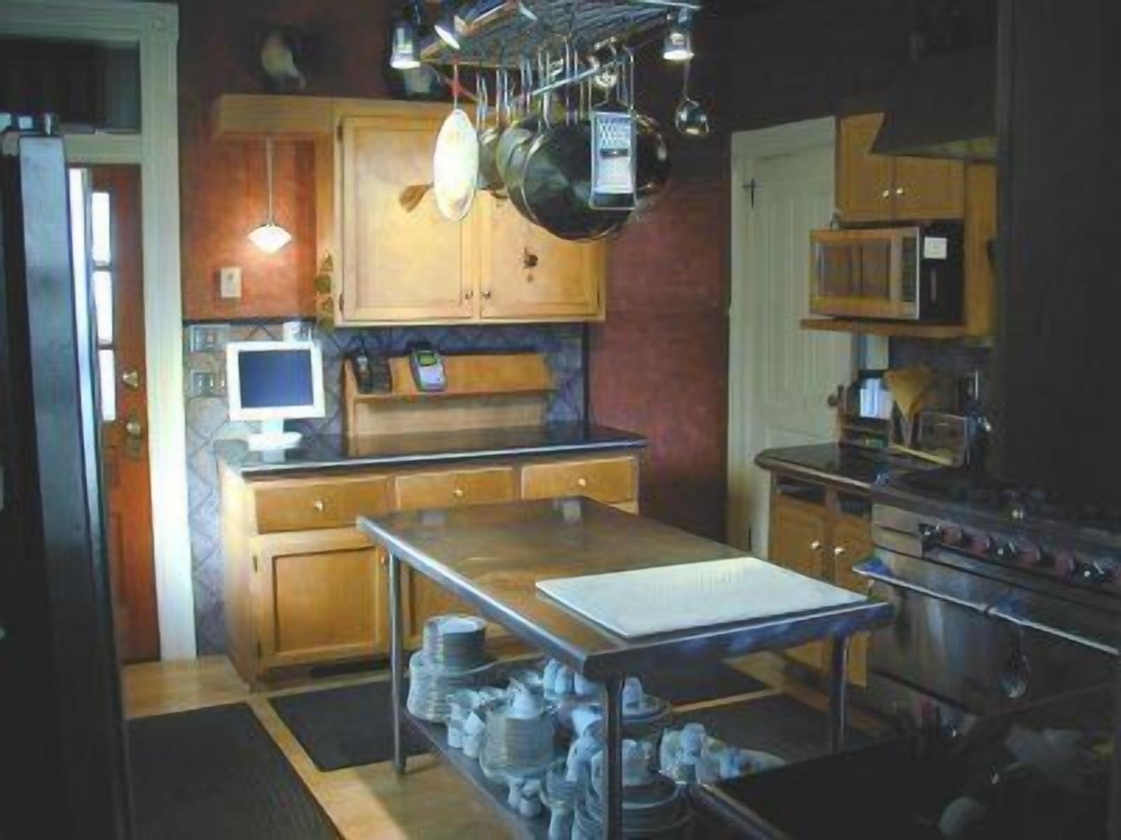 Una cocina con armarios de madera, una mesa de acero inoxidable, un microondas y una estufa.