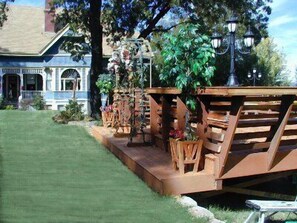 A wooden deck with a railing, surrounded by potted plants and a street lamp. - Robin's Nest Inn (San Andreas)