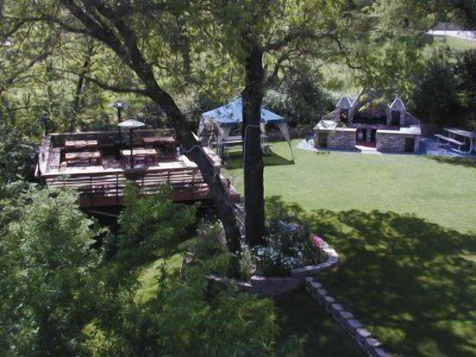 A wooden deck with a covered seating area, surrounded by a well-maintained lawn and trees.