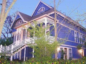 A large, two-story house with a steeply pitched roof, a prominent front porch, and a staircase leading to the entrance. - Robin's Nest Inn (San Andreas)