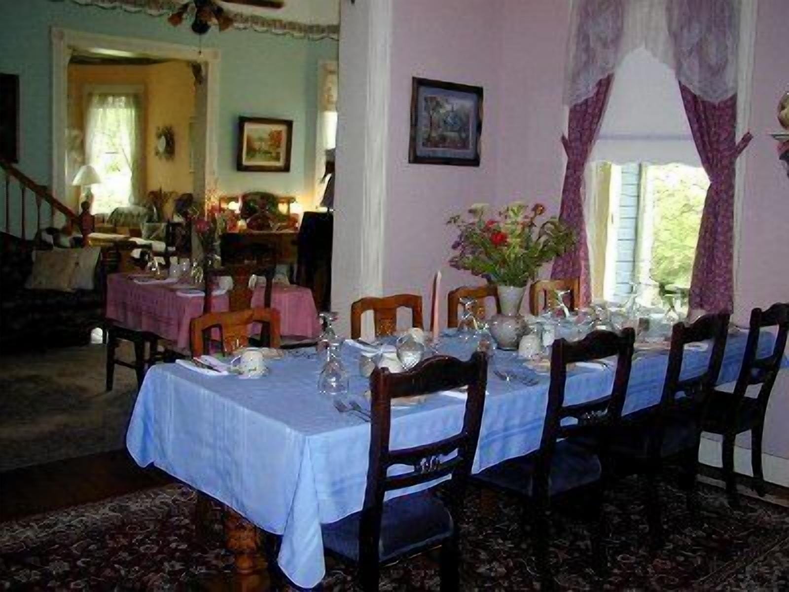 A dining room with a table set for six, surrounded by chairs.