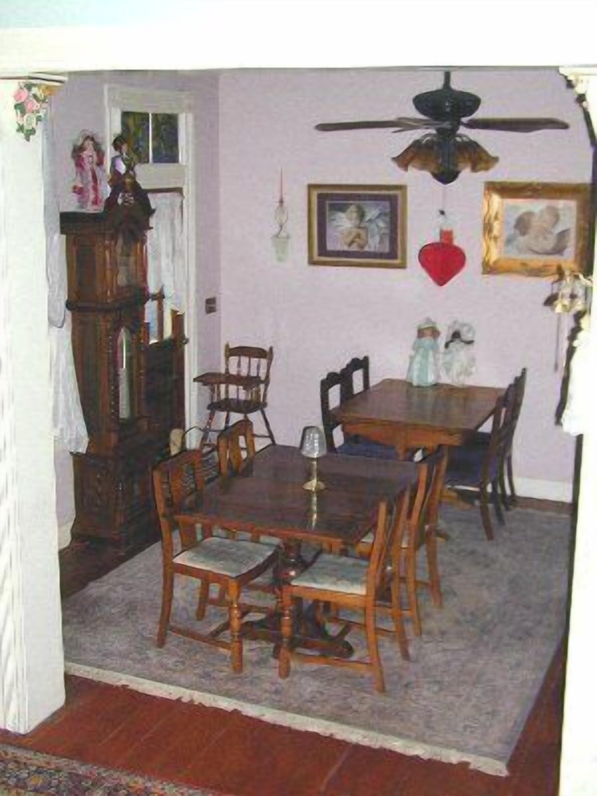 A dining area with a wooden table and chairs, a ceiling fan, and a clock on the wall.