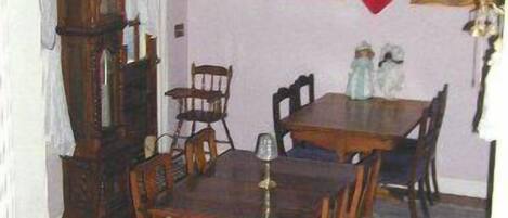 A dining area with a wooden table and chairs, a ceiling fan, and a clock on the wall.