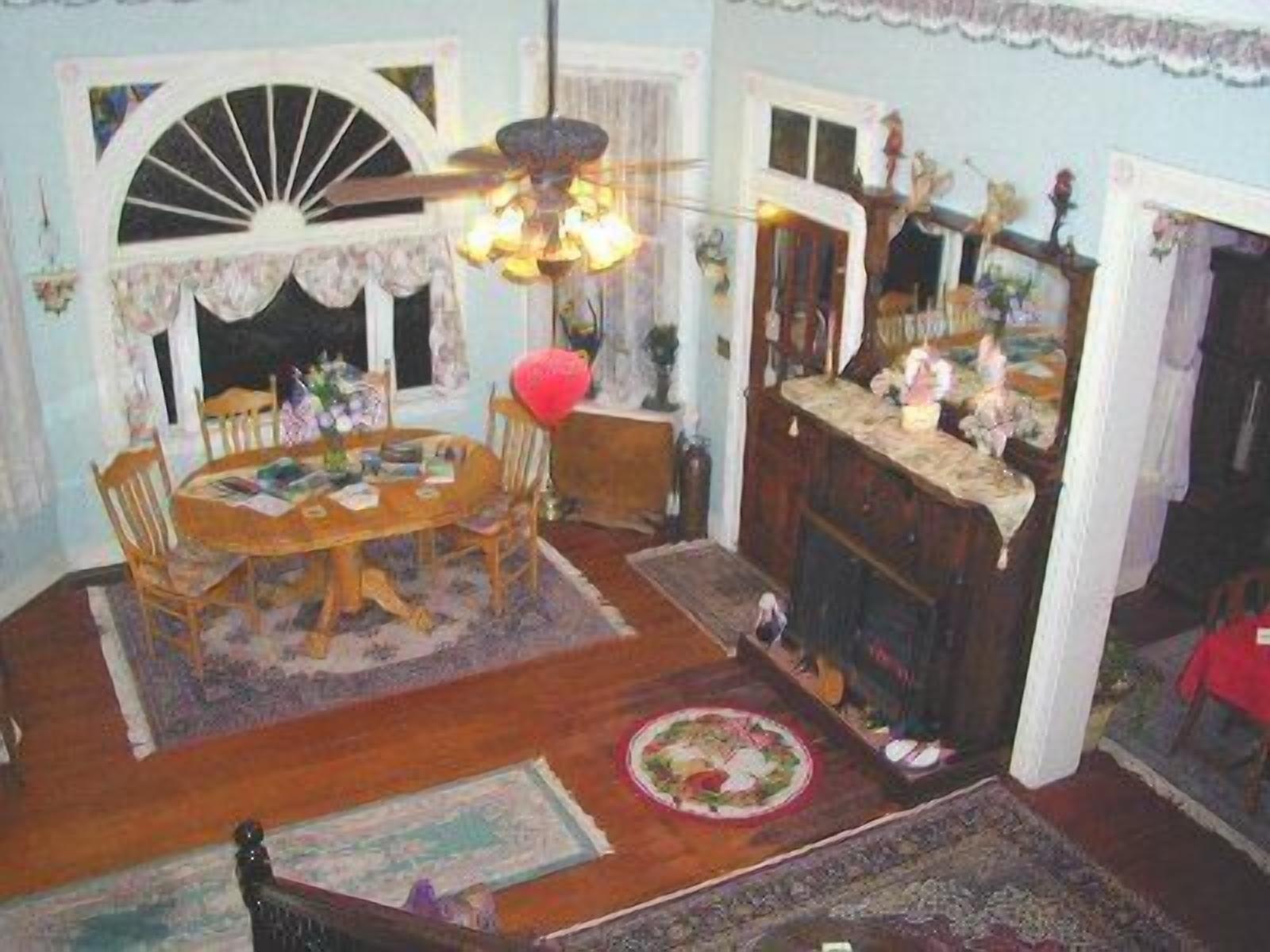 A dining room with a wooden table, chairs, a chandelier, and a fireplace.