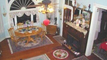 A dining room with a wooden table, chairs, a chandelier, and a fireplace.