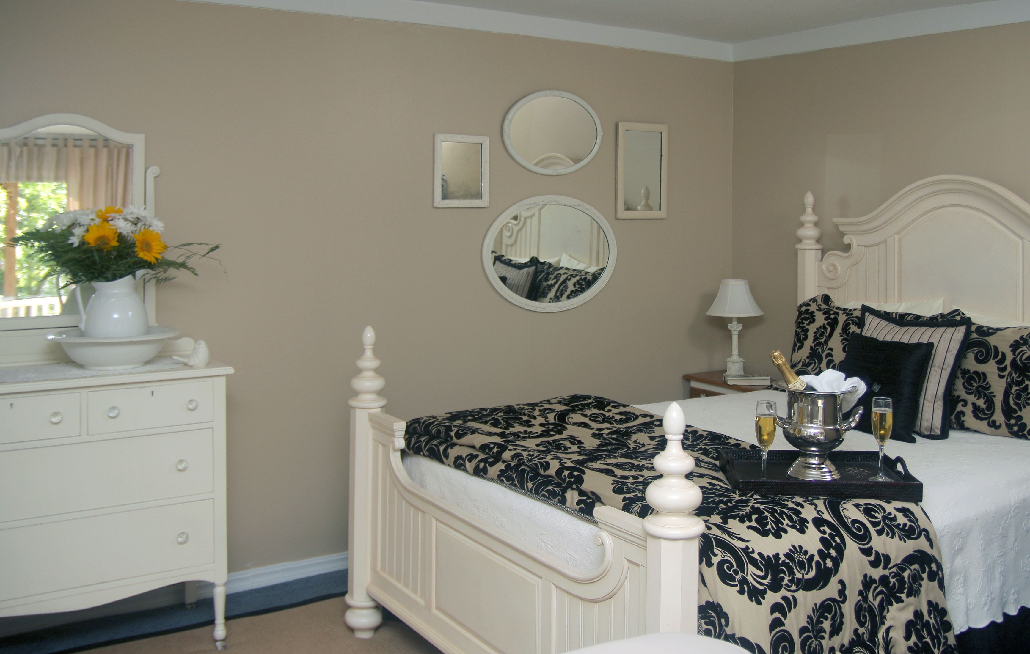 A bedroom with a bed, dresser, and a vase of flowers.
