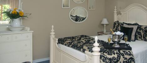 A bedroom with a bed, dresser, and a vase of flowers.