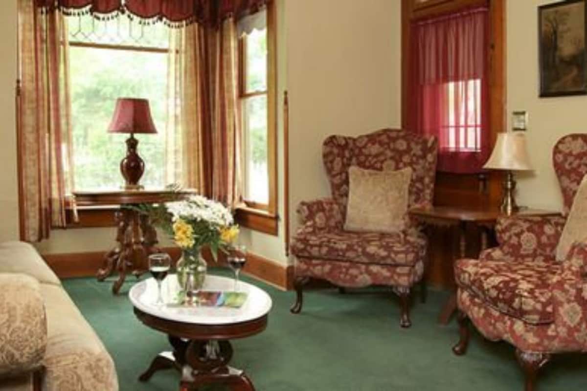Een klassieke woonkamer met meubels met bloemmotieven, een ronde salontafel en een raam met gordijnen.