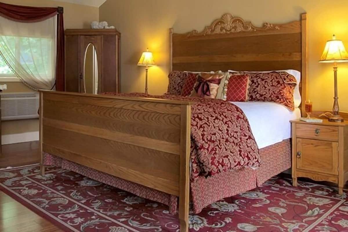 Een houten bed met een beddengoed met patroon, twee bedlampen en een nachtkastje met een lamp.