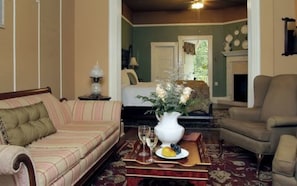 A cozy living room with a sofa, armchair, and a coffee table with a vase of flowers. - Heartstone Inn B&B & Cottages (Eureka Springs)