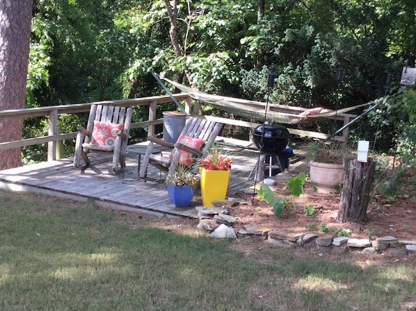 A wooden deck with rustic chairs and a barbecue grill.