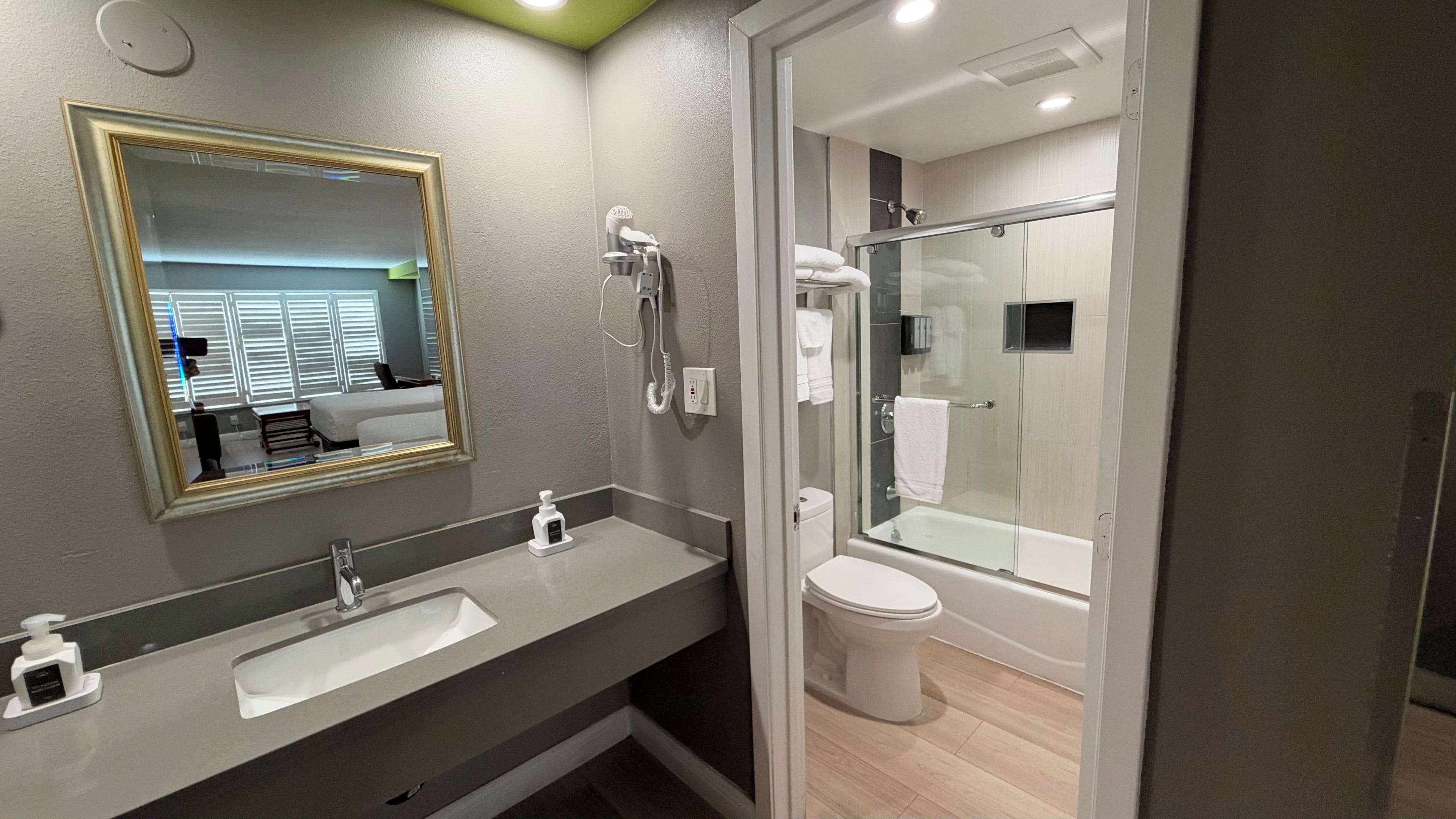 A modern bathroom with a large mirror, a sink, a toilet, and a glass-enclosed shower area.