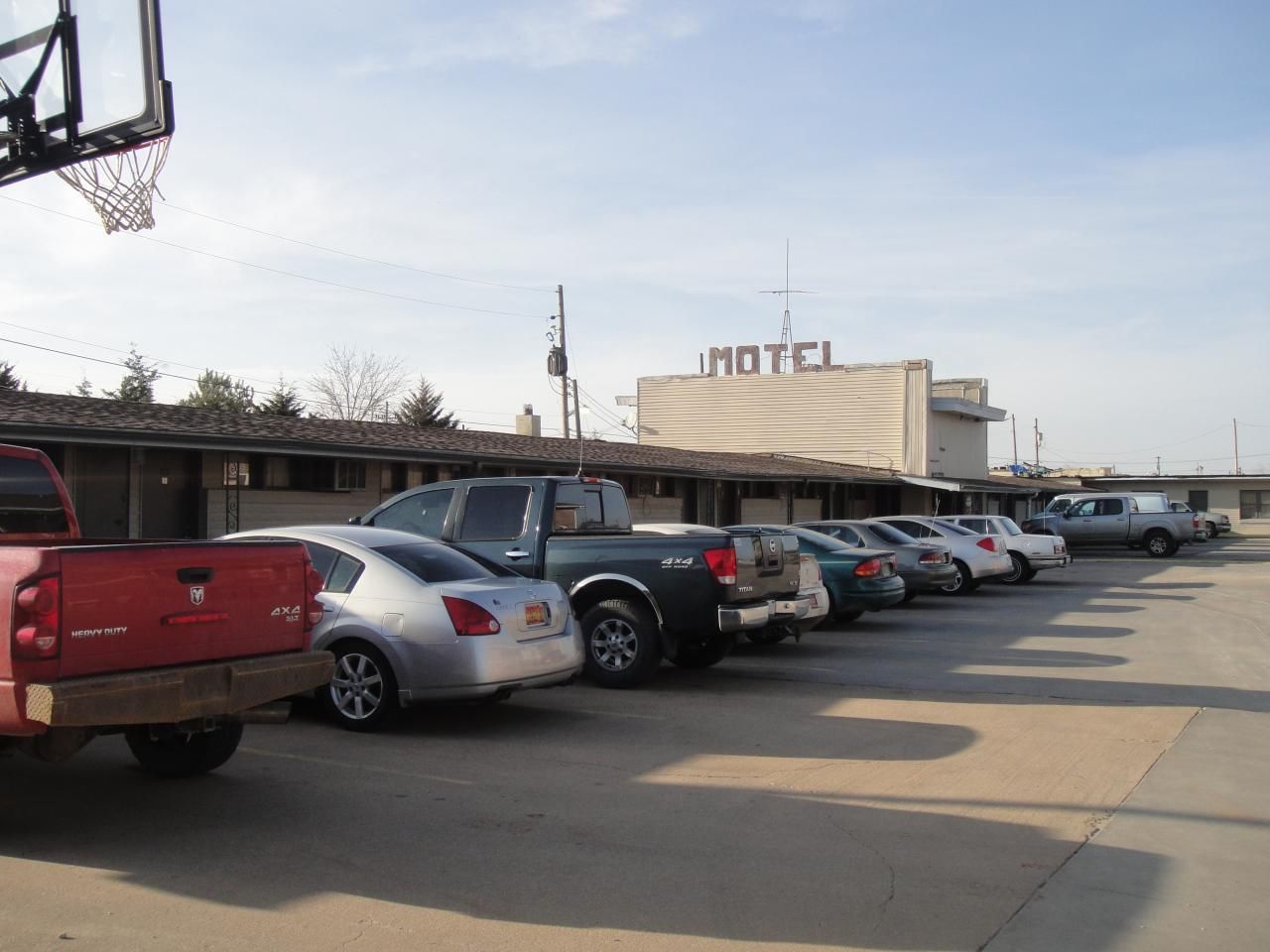 Een rij geparkeerde auto's voor een motel met een eenvoudig, functioneel ontwerp.