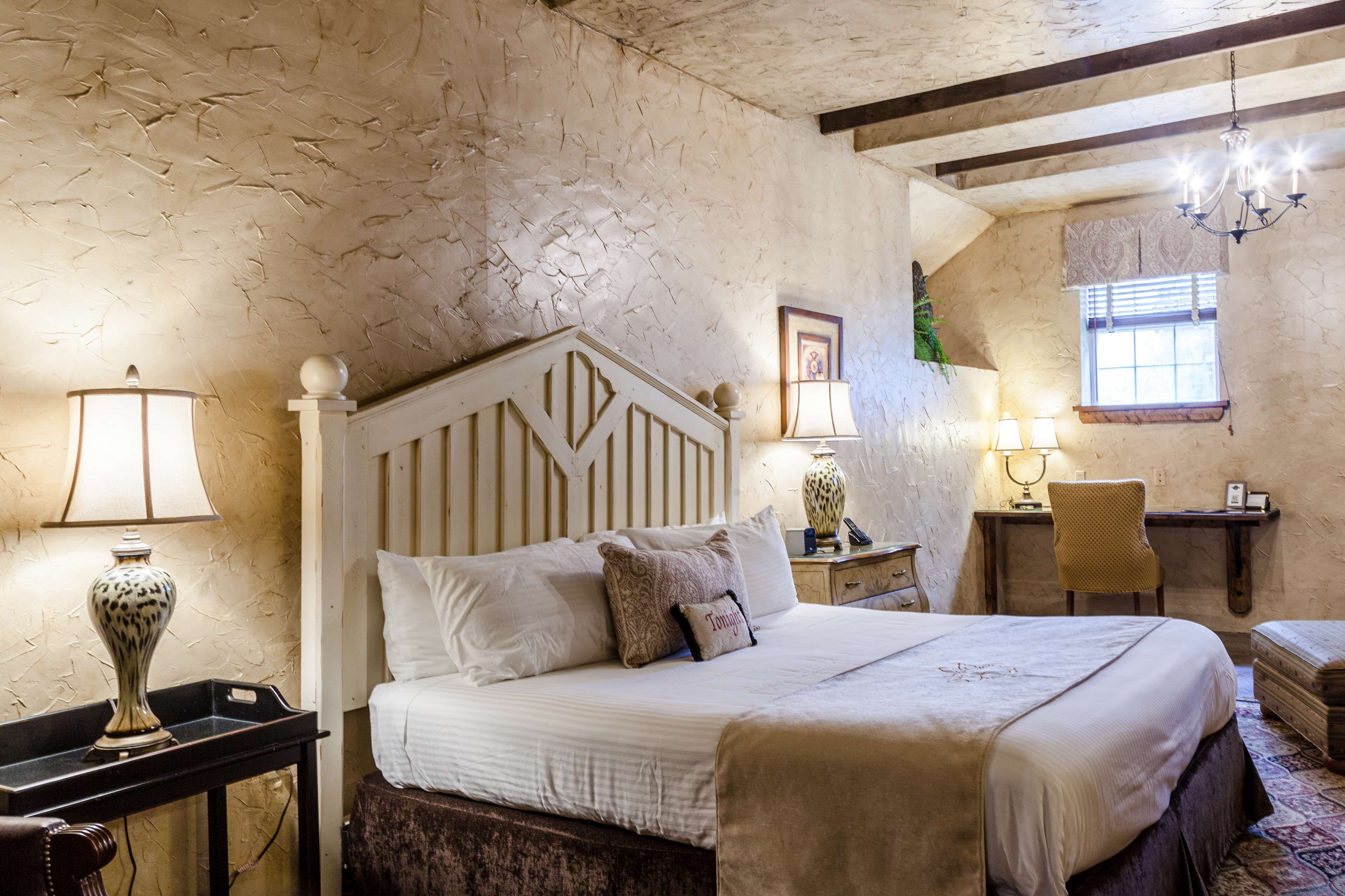 Une chambre à coucher avec un grand lit, une table de chevet, une chaise, un bureau et un lustre.