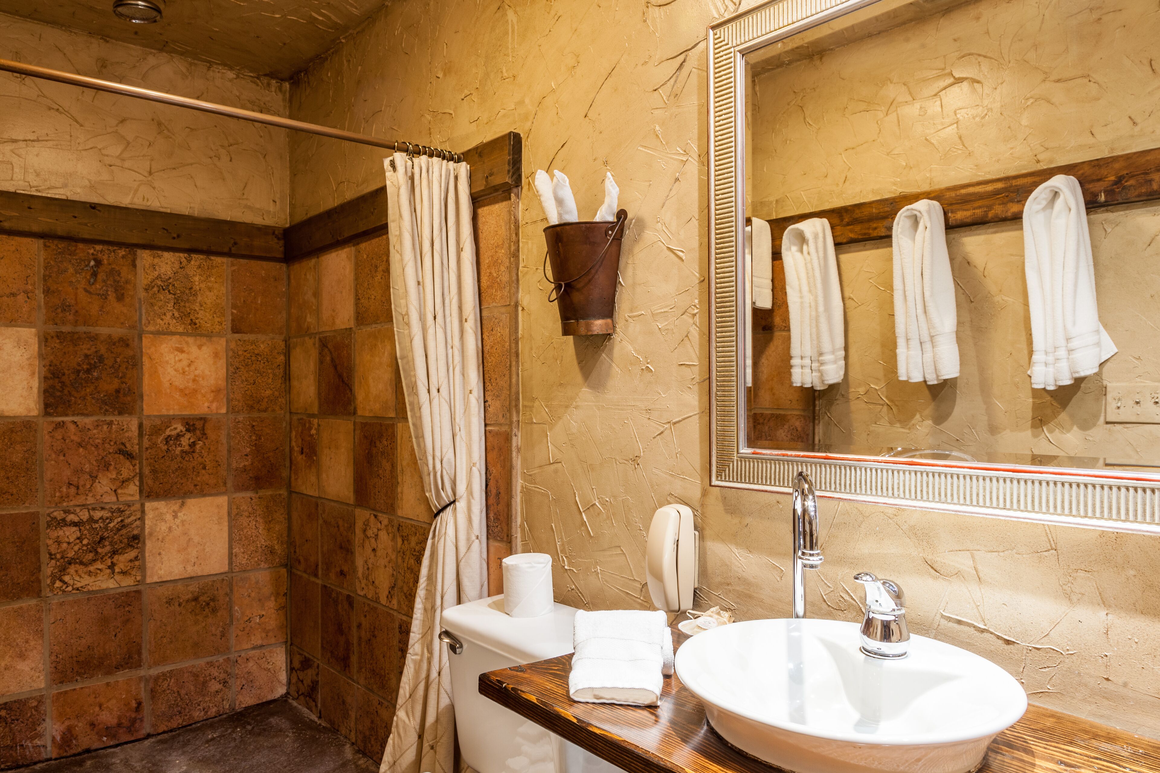 Une salle de bain équipée d’une douche, de toilettes, d’un lavabo et d’un miroir.