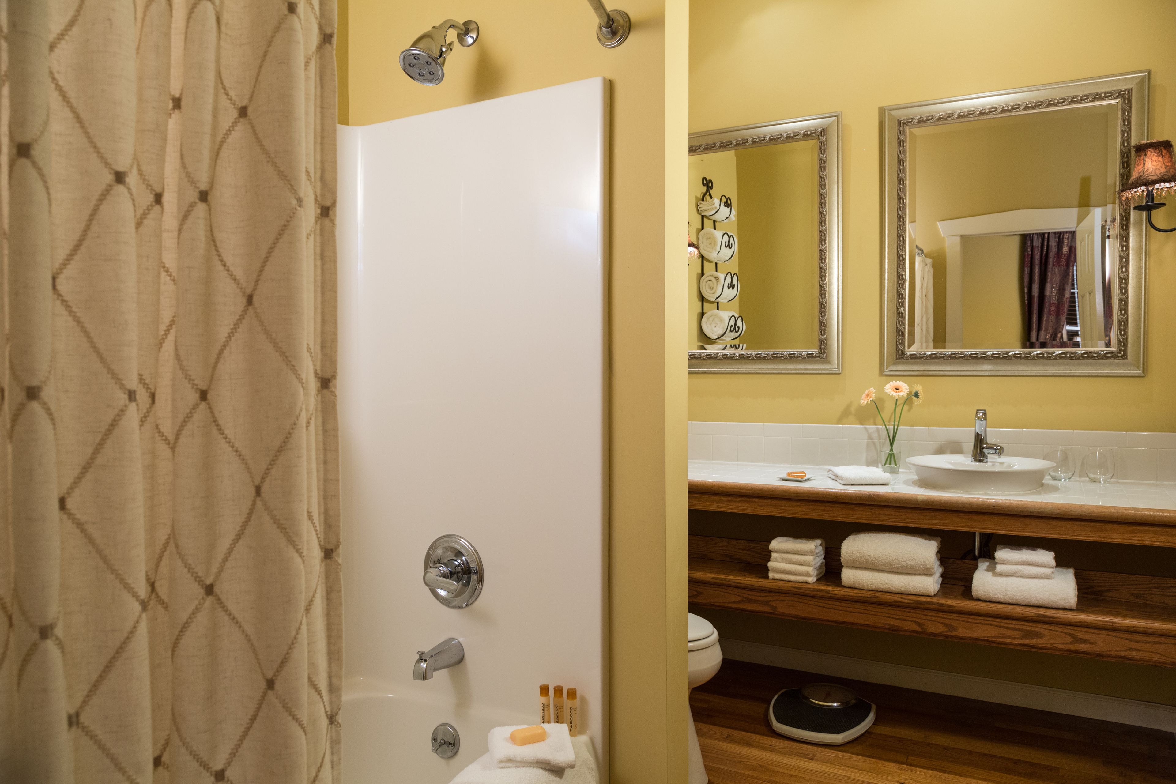 A bathroom with a shower, toilet, and sink. There are towels and toiletries on the sink counter.