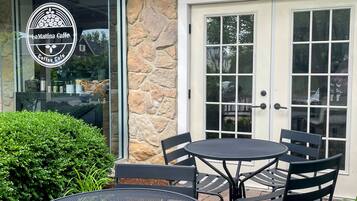 An outdoor seating area with a stone wall, a glass door, and a sign for LaMattina Caffe.