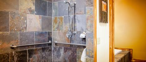 A shower area with a handrail, a towel rack, and a wooden frame around the shower door.