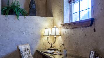 A room with a textured wall, a window with a view, a lamp, a chair, and a plant.