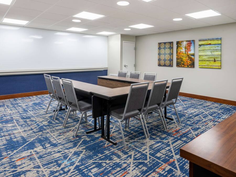 A conference room with a large table, chairs, a whiteboard, and three paintings on the wall.